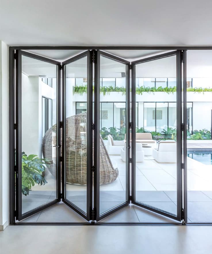 An aluminium bi-fold door folded fully back onto a courtyard, clearing the whole opening