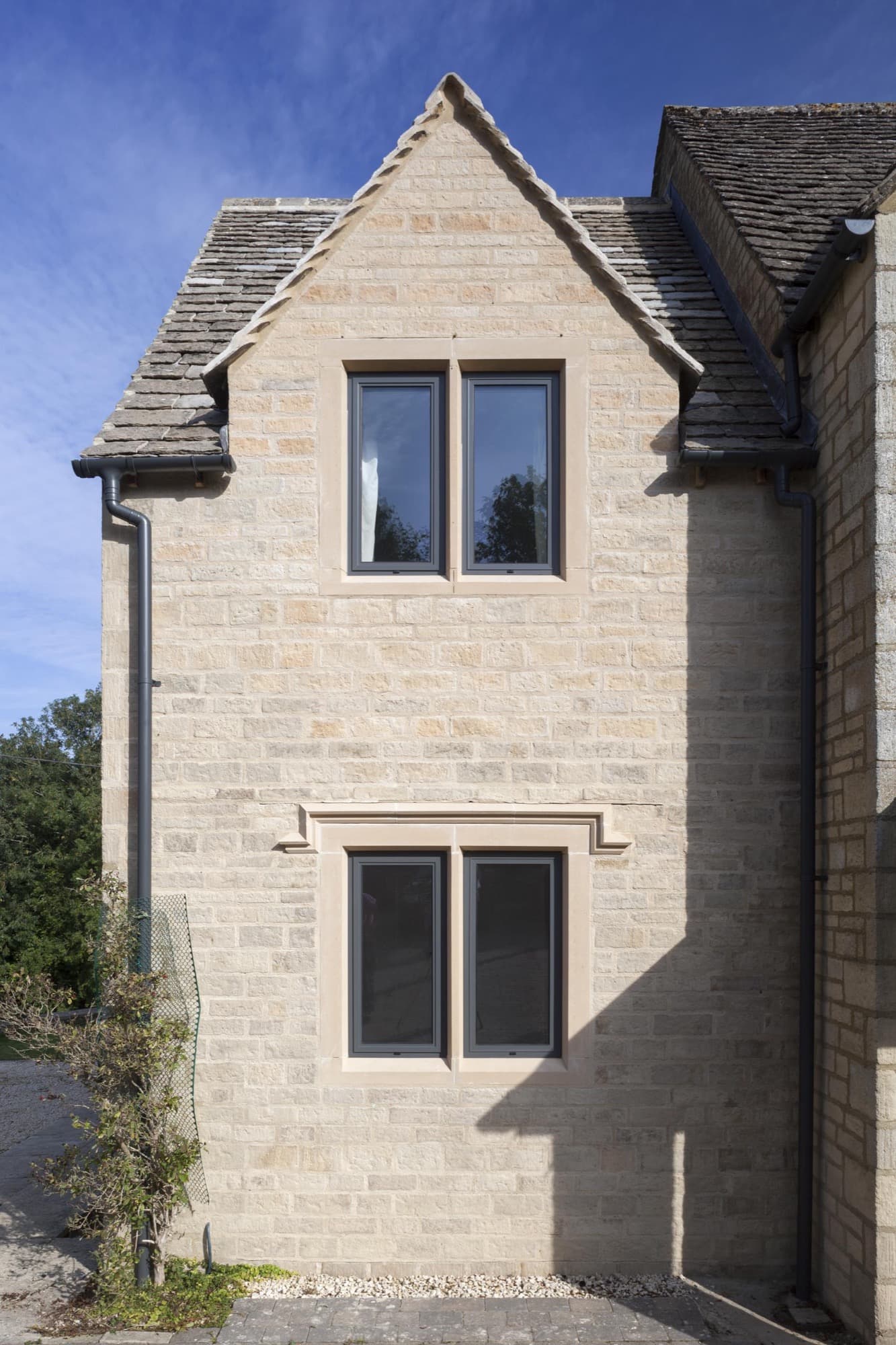 The gable end of a stone house fitted with aluminium casement windows