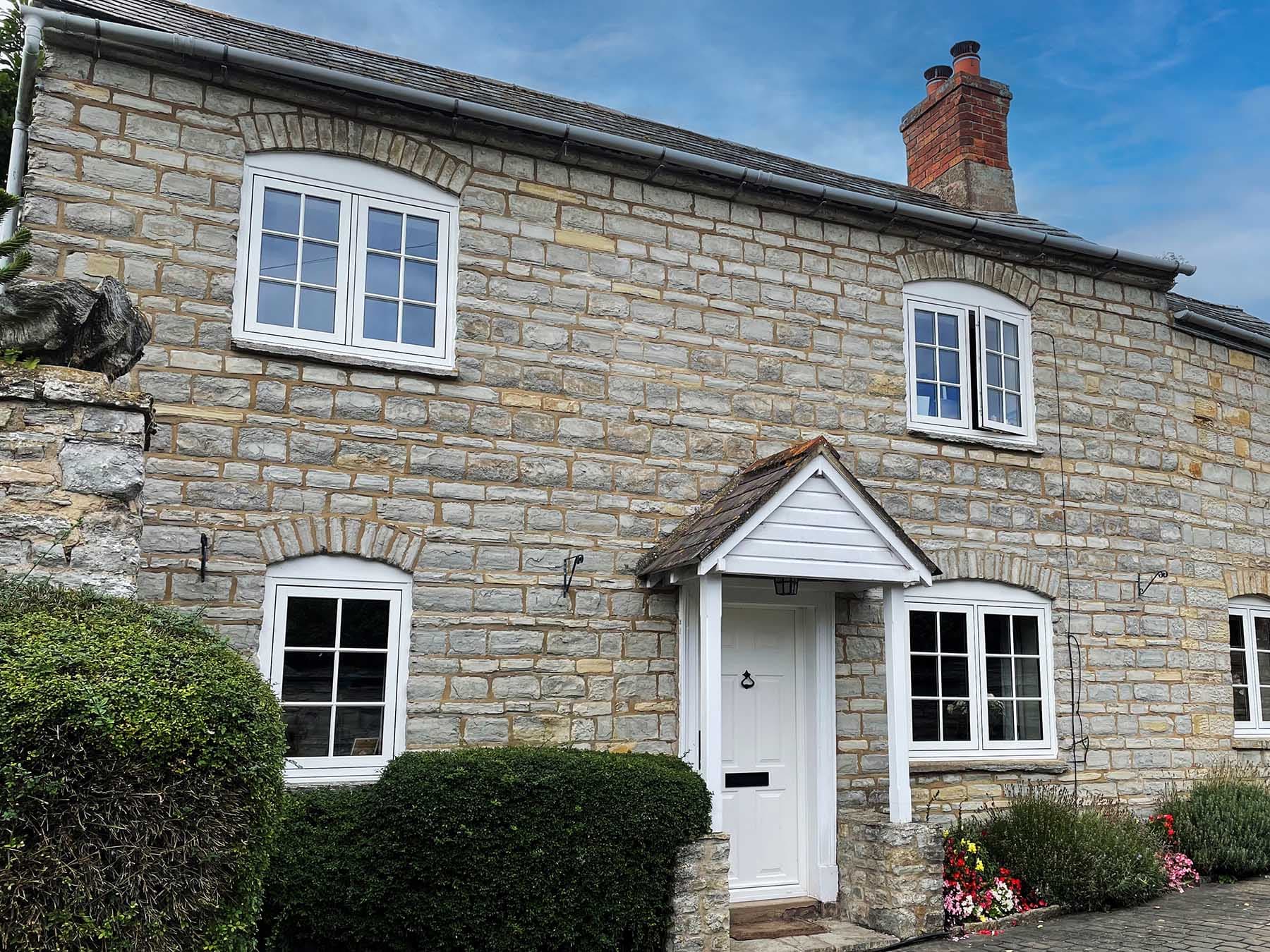 Cream flush casement windows with glazing bars in a stone cottage elevation