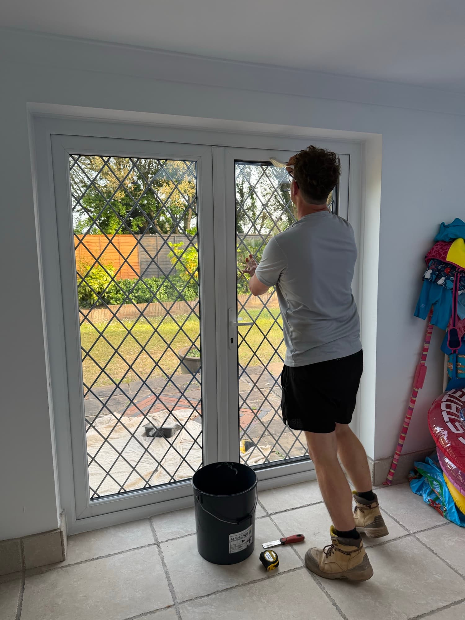 A Wilshaw fitter working on a french door from inside the room, mid-repair