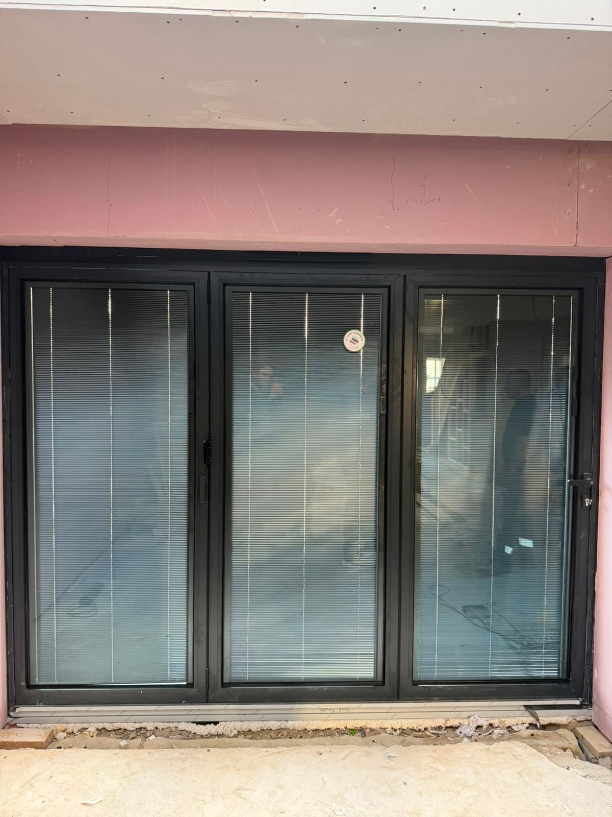 A bright room with full-height black aluminium bi-fold doors and integral blinds, fitted by Wilshaw Glazing