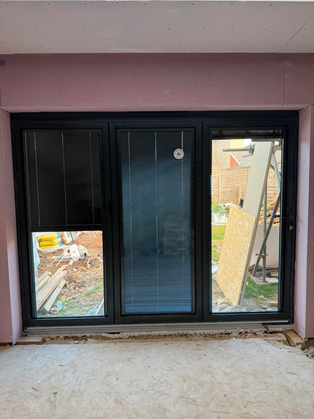 Full-height black aluminium doors in a bright open-plan room, fitted by Wilshaw Glazing