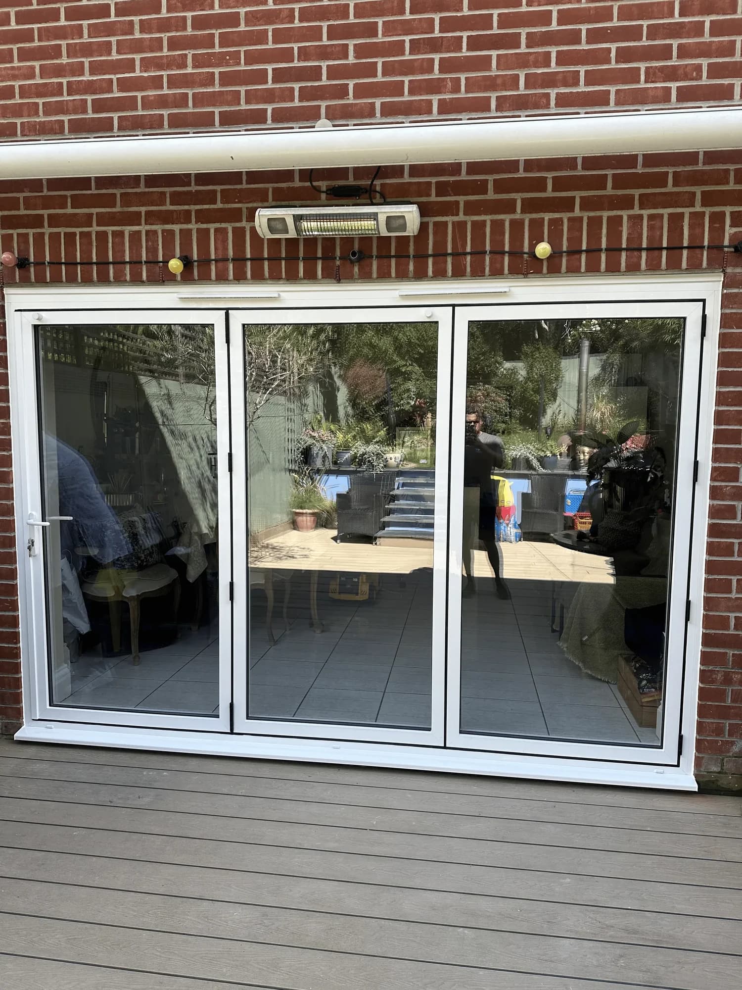 A white aluminium three-pane bi-fold door opening onto a composite deck, a real Wilshaw installation