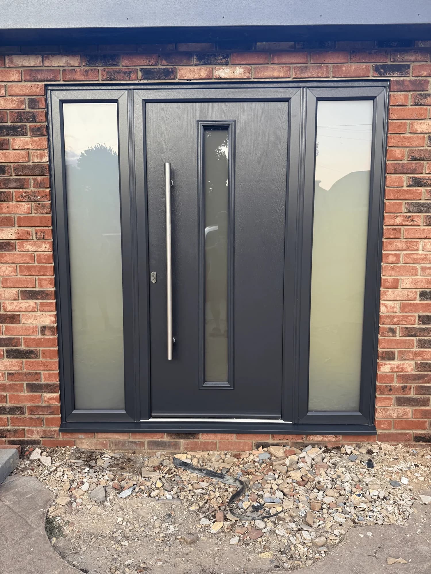 An anthracite composite front door with a long bar handle and two obscure-glazed sidelights, a real Wilshaw installation