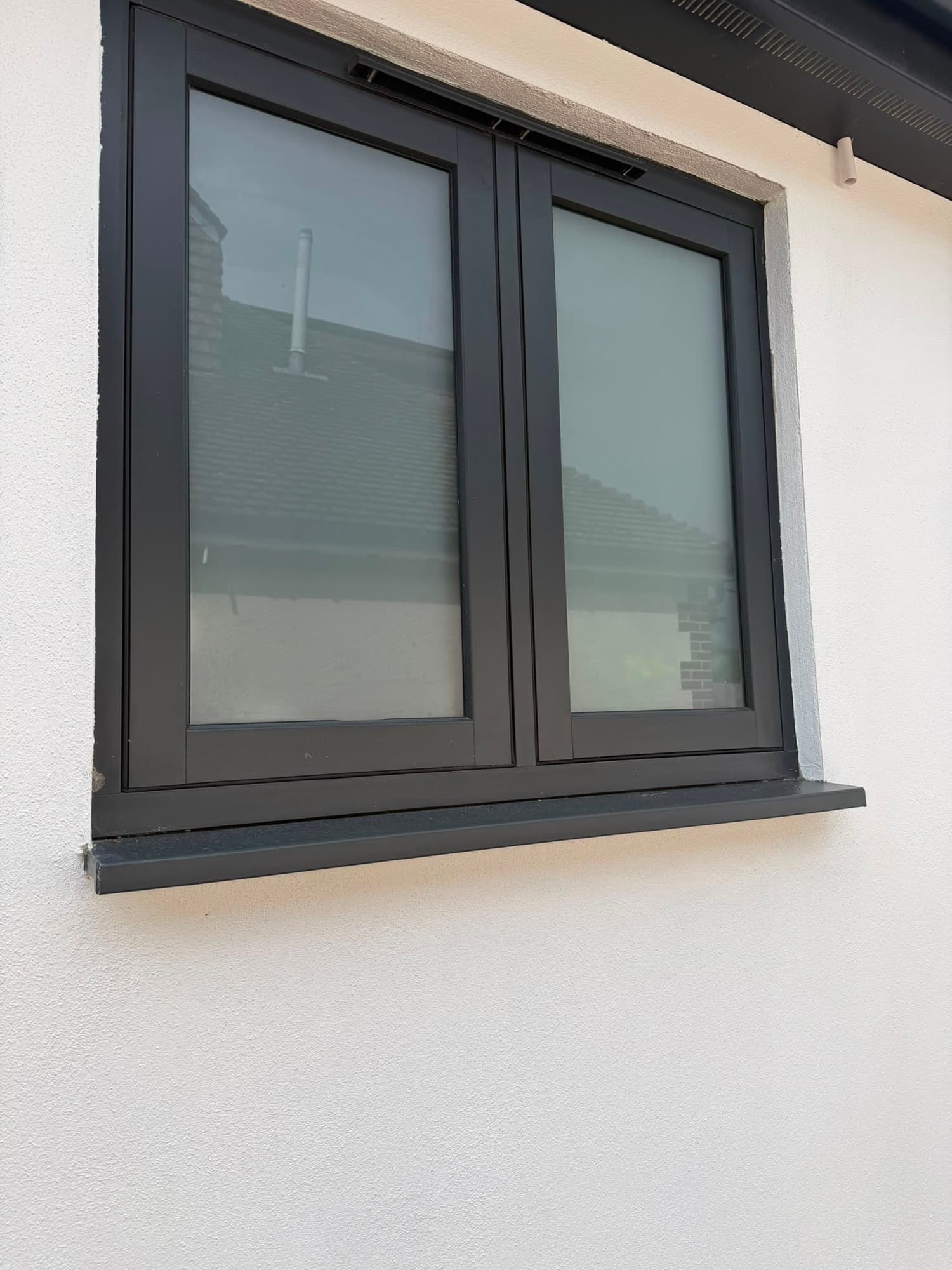 A close-up of an anthracite flush casement, the sash sitting flush with its outer frame, fitted by Wilshaw Glazing