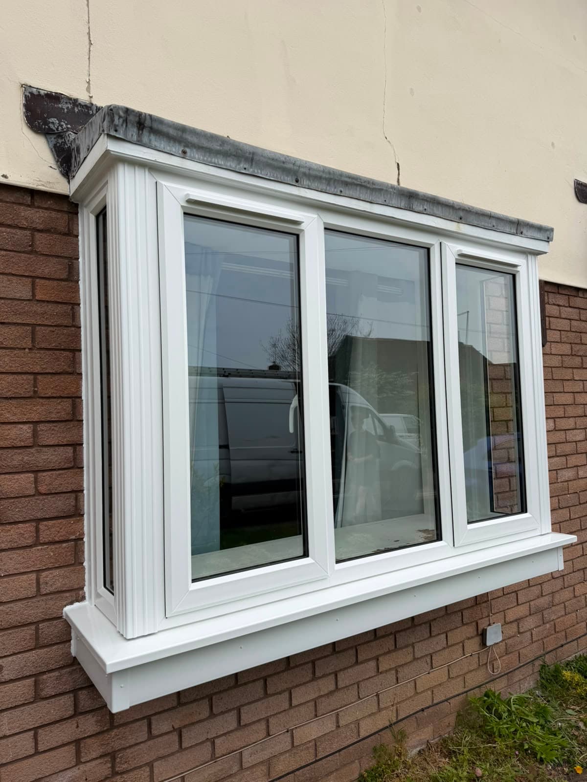 A white uPVC three-pane bay window in a brick elevation, fitted by Wilshaw Glazing