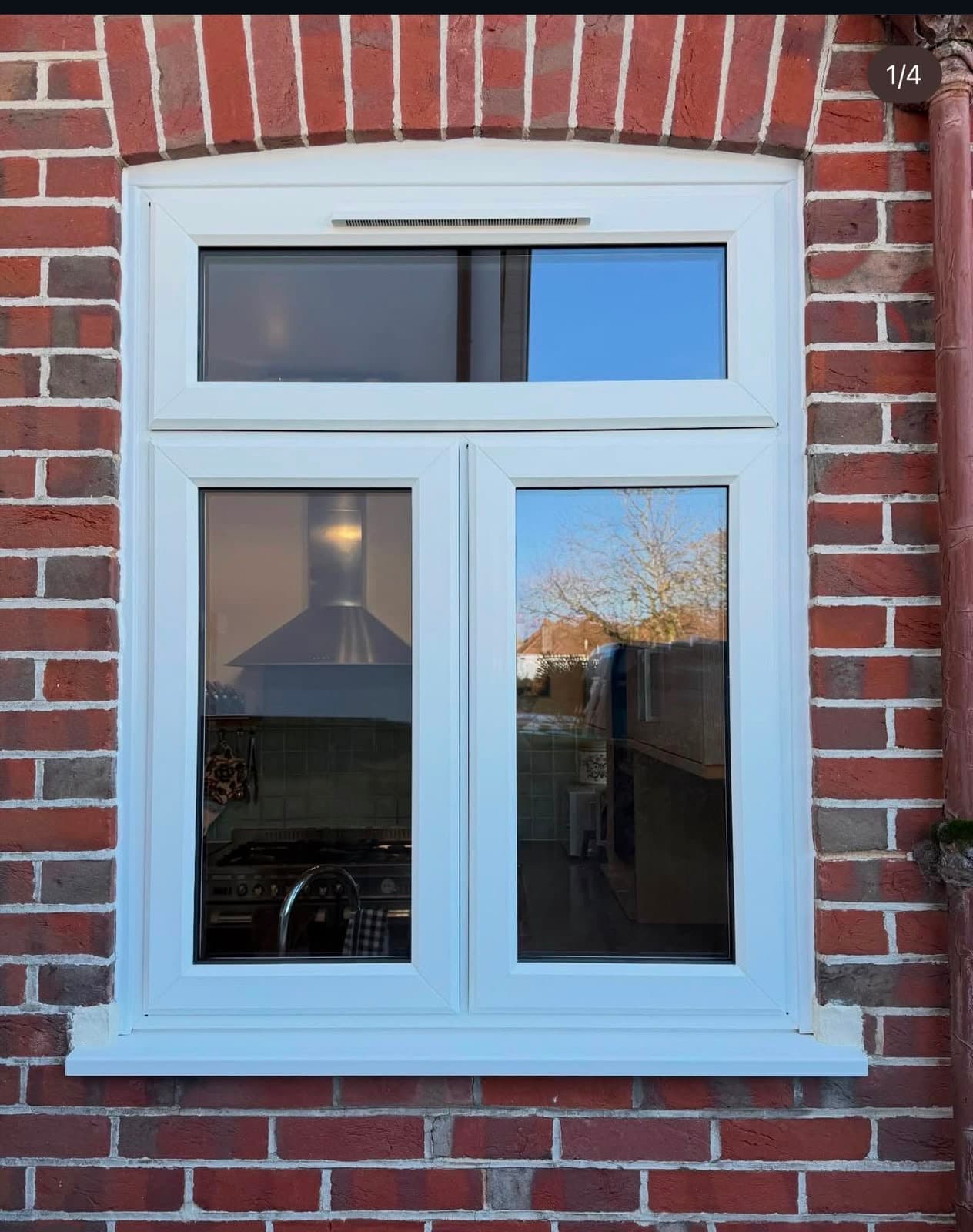 A white uPVC casement window in an arched brick opening, a real Wilshaw installation