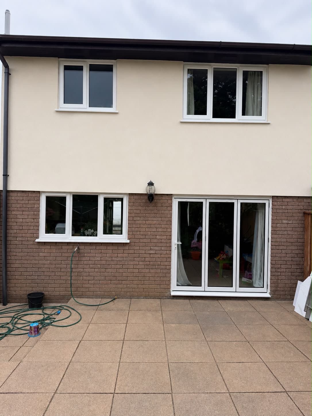 A rendered rear elevation with new white uPVC windows onto a patio, a real Wilshaw installation