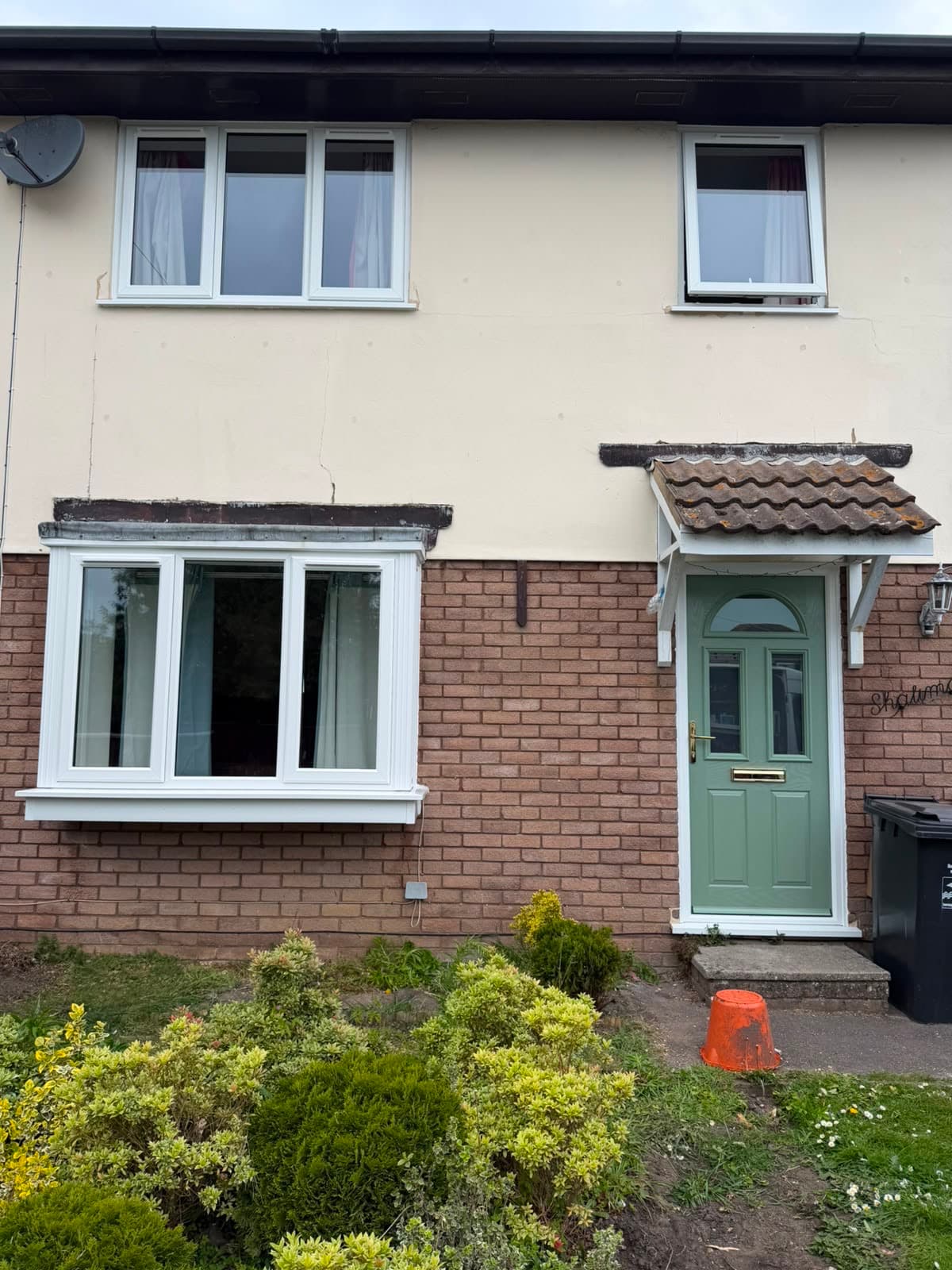 A cream-rendered semi-detached frontage fitted with new white uPVC windows, a real Wilshaw installation
